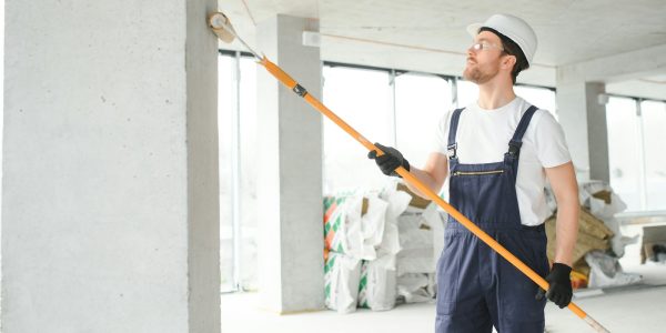 Worker renewing apartment on wall background.